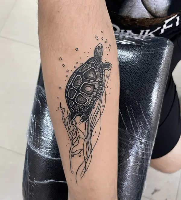 Black turtle with bubbles and line-art seaweed forearm tattoo by Diya Tattoo, Kathmandu