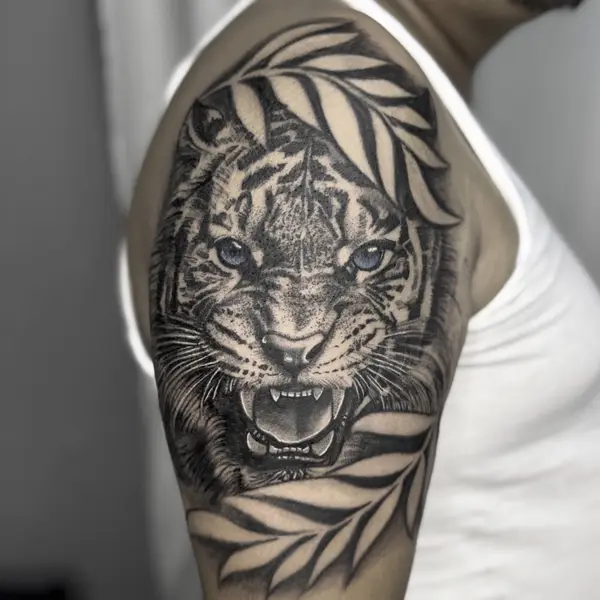 Realistic roaring tiger shoulder tattoo with blue eyes and leaves by Diya Tattoo, Kathmandu